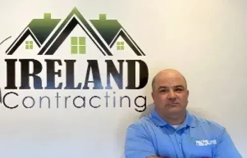 Adam Chelli, salesperson at Ireland Contracting, standing in front of the company logo.