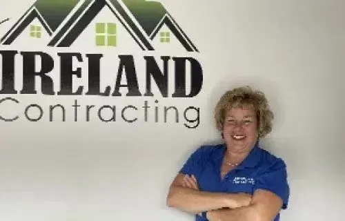 Diane Ireland of Ireland Contracting, smiling with arms crossed in front of the company logo.