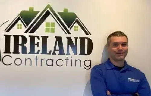 Tim Barch, Sales Manager at Ireland Contracting, standing in front of the company logo.