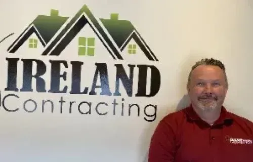 Tom Dunne, salesperson at Ireland Contracting, standing in front of the company logo.